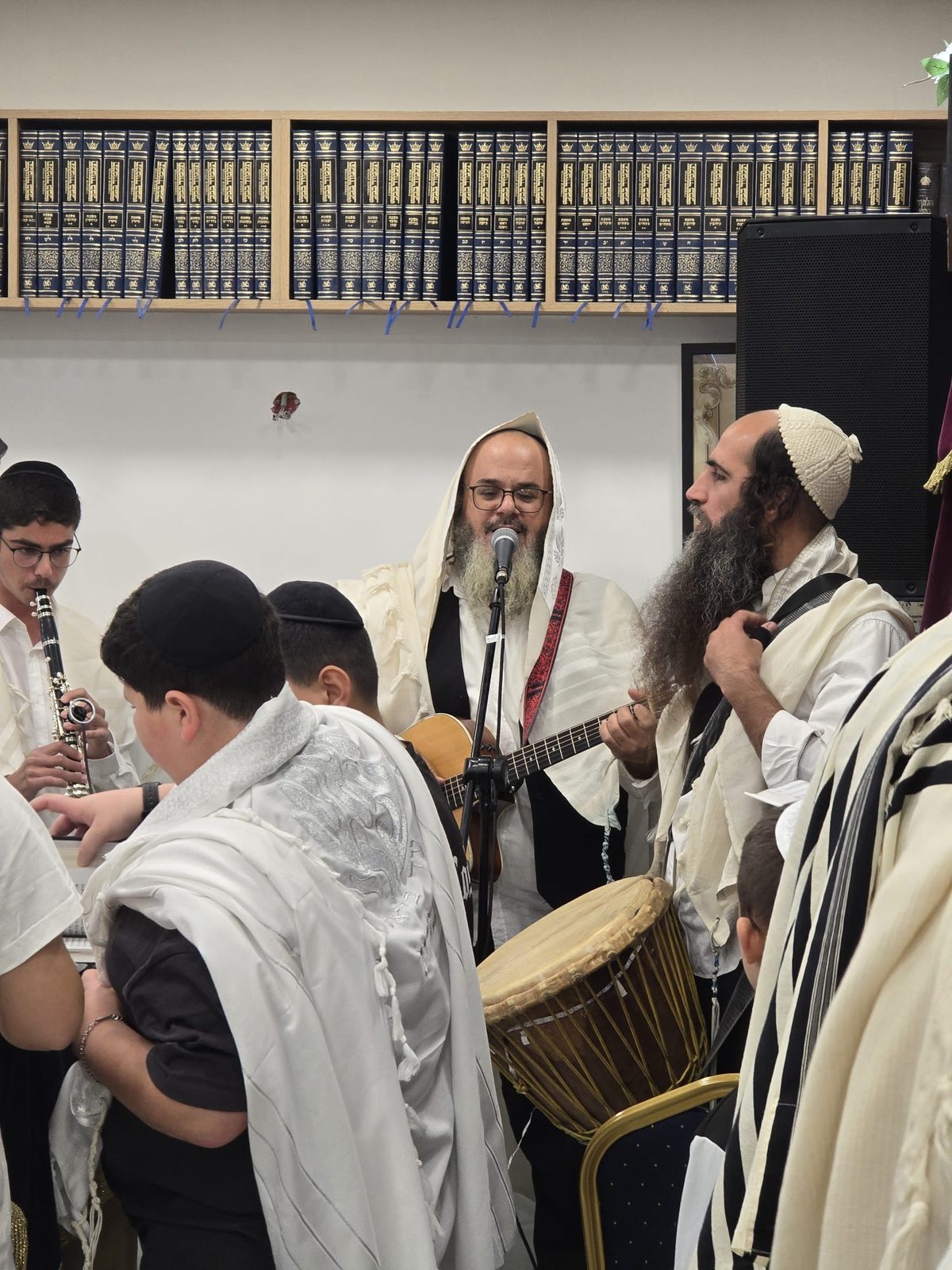 Le Rav chante à la guitare, accompagné d’une clarinette et d’une darbouka, fidèles en talit