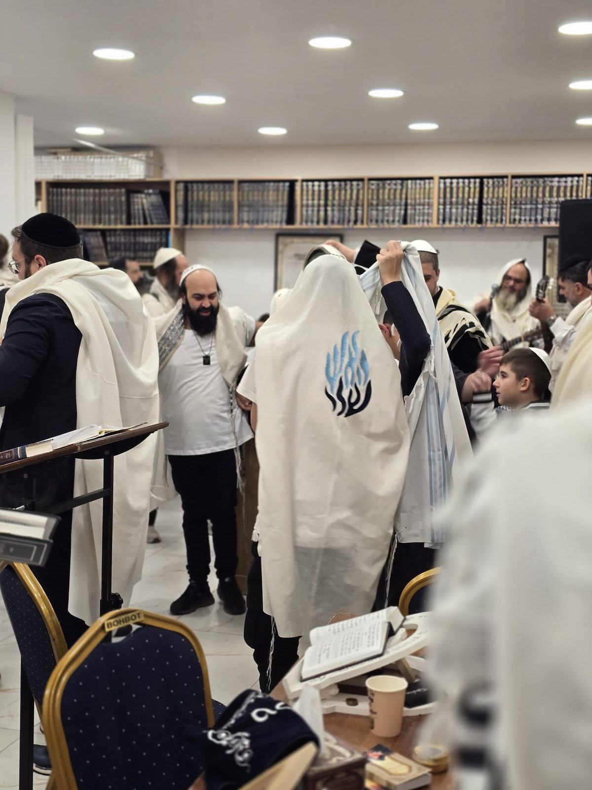 Fidèle enveloppé dans son talit au centre de la synagogue, la communauté autour